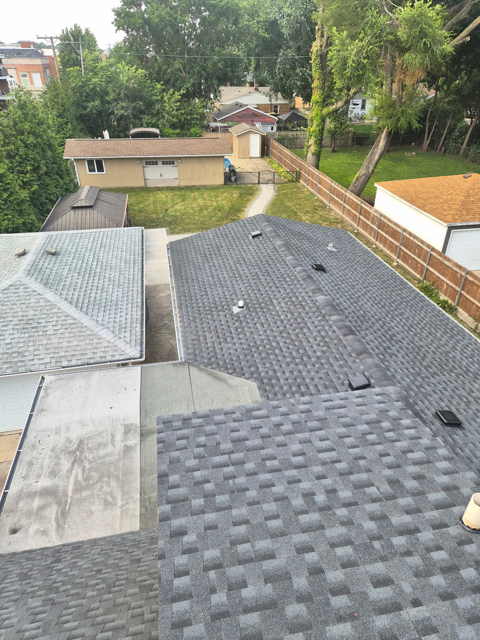 Aerial view of a completed multi-section residential roof replacement in the Chicago area, showing several shingled roof planes, a low-slope section, and plumbing vent boots